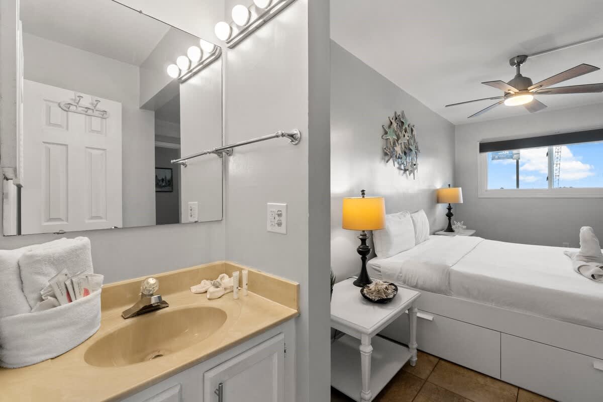 The Summit 620 – Bedroom with a bed, lamps, and a bathroom mirror; window view of the sky.