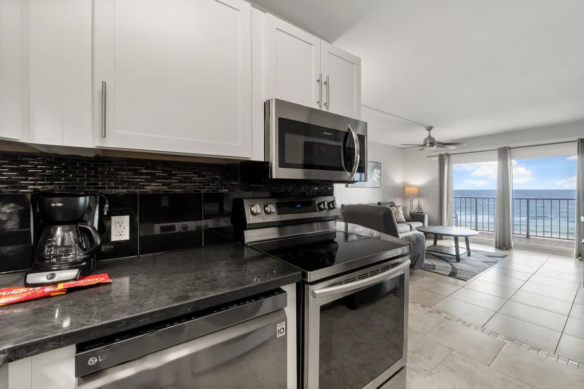 The Summit 620 – Modern kitchen view with stainless steel appliances and ocean view through large sliding glass doors.