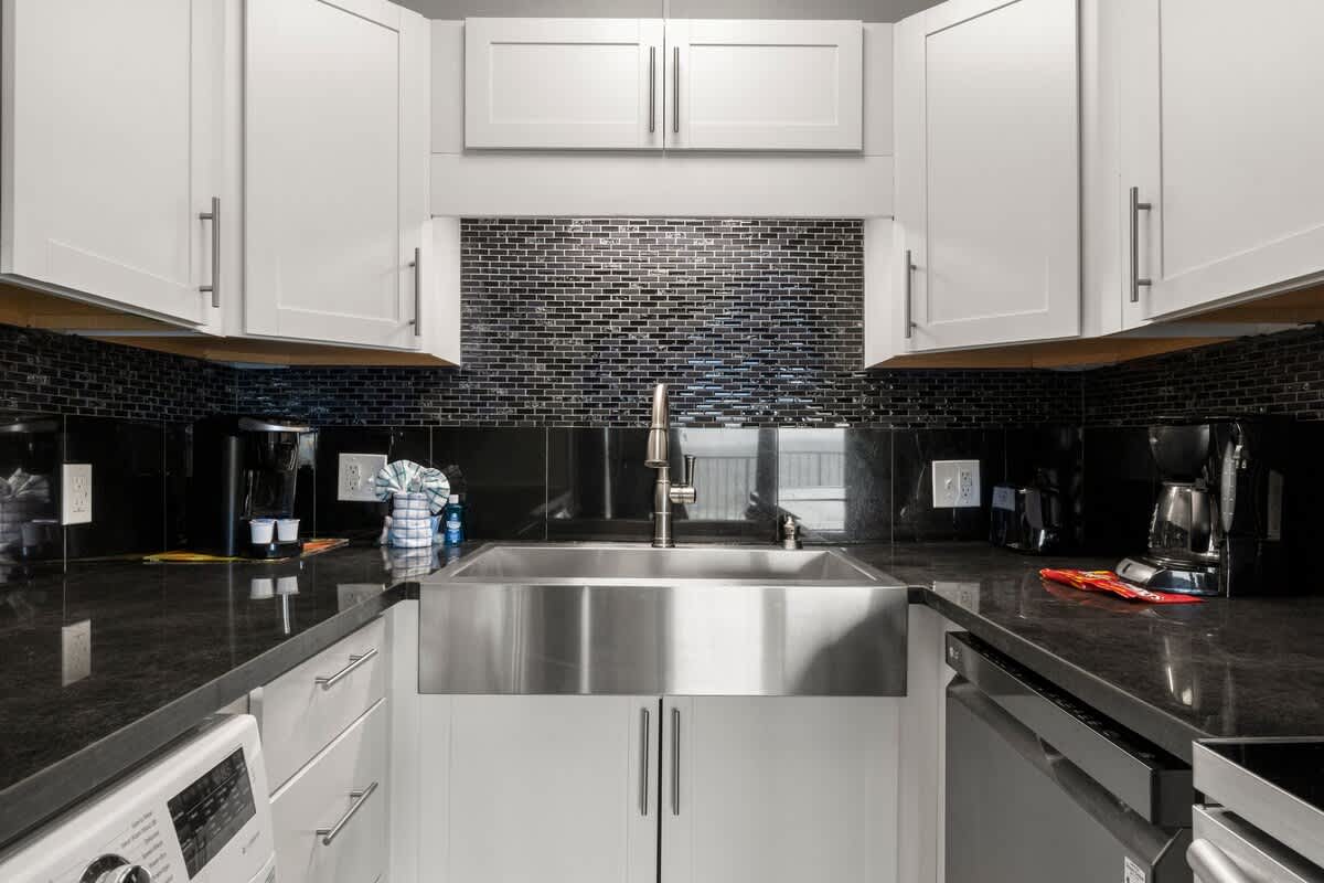 The Summit 620 – Modern kitchen with stainless steel sink, black countertops, and white cabinets.