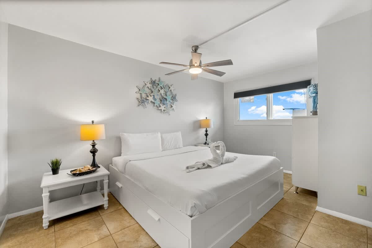 The Summit 620 – Bright bedroom with a queen bed, nightstands, and a window showing a blue sky view.