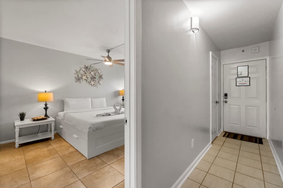 The Summit 620 – Entryway leading to a bedroom with a bed, lamps, and decorative wall art.
