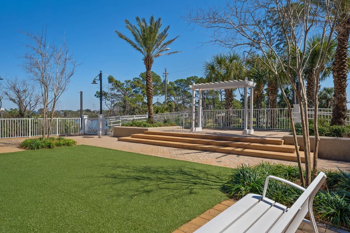 Laketown Wharf 1331 – Outdoor terrace with green lawn, palm trees, seating area, and steps leading to a gazebo.