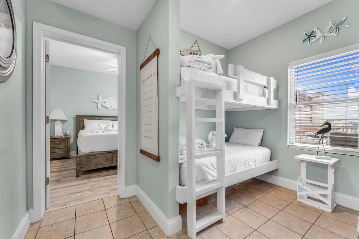 Laketown Wharf 1331 – Cozy bedroom with a bunk bed, a queen bed visible through the doorway, and natural light from a window.