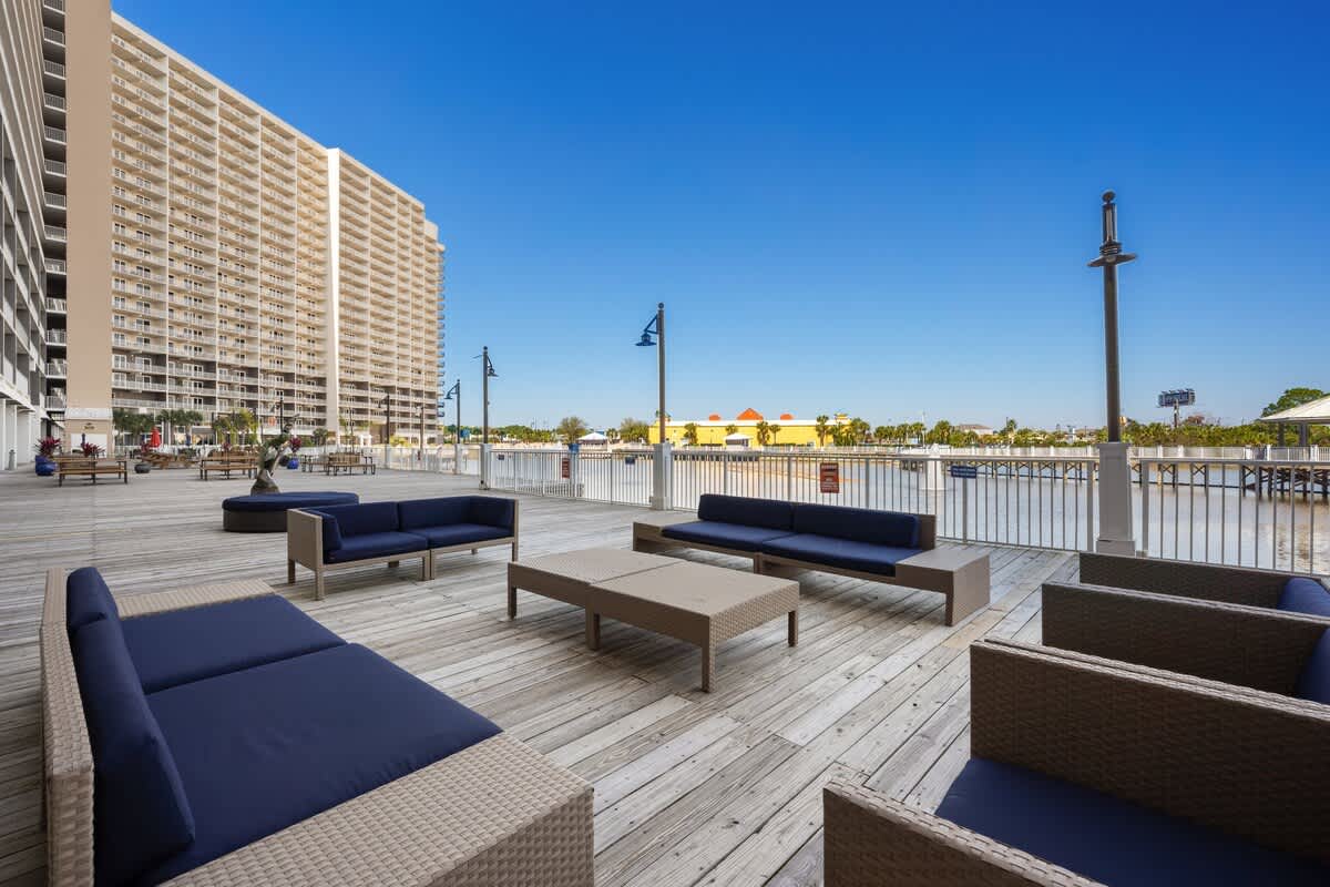 Laketown Wharf 1331 – Outdoor seating area with navy cushions, wooden deck, views of the water and nearby buildings.