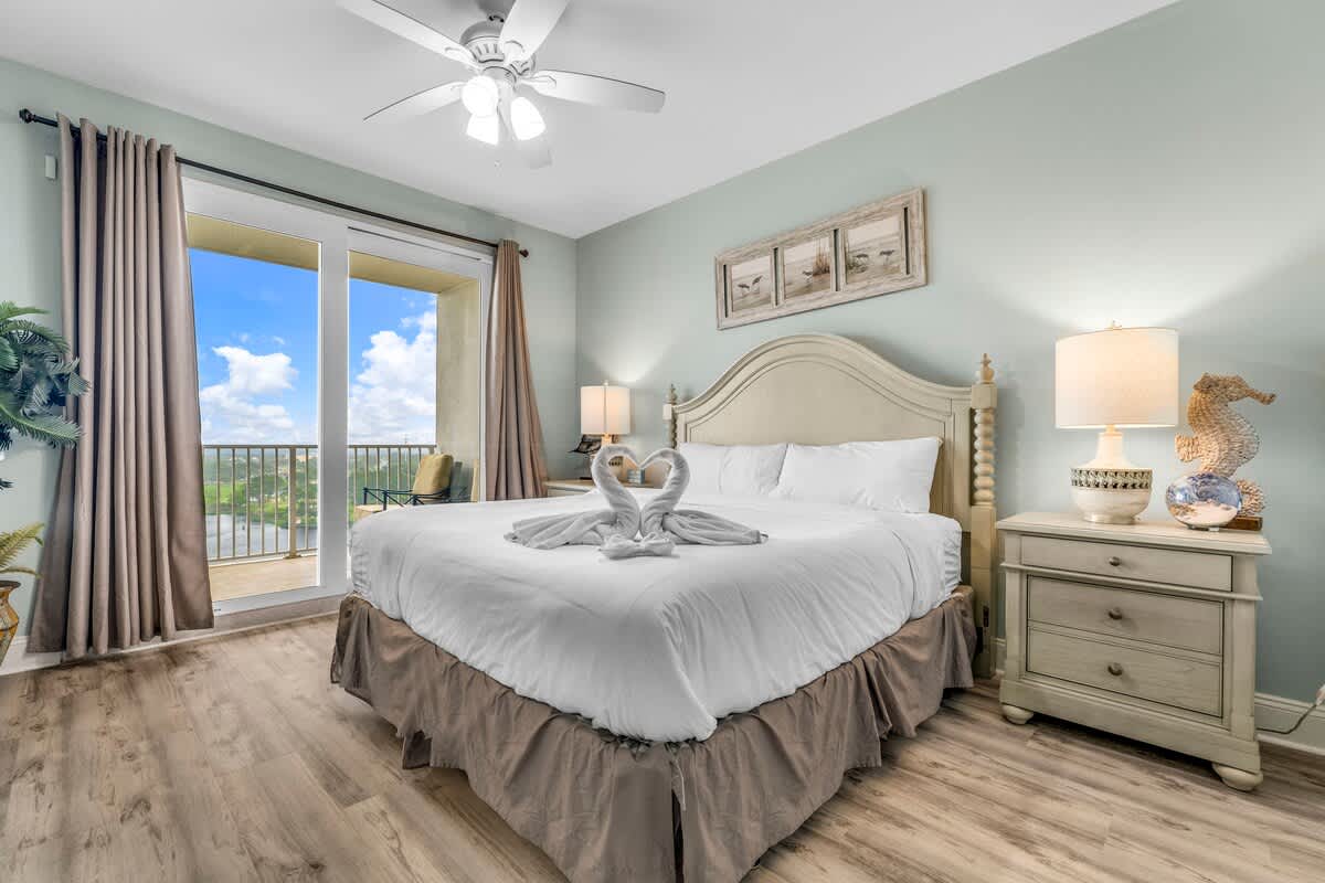 Laketown Wharf 1331 – Bedroom with a king bed, balcony view, and light blue walls.