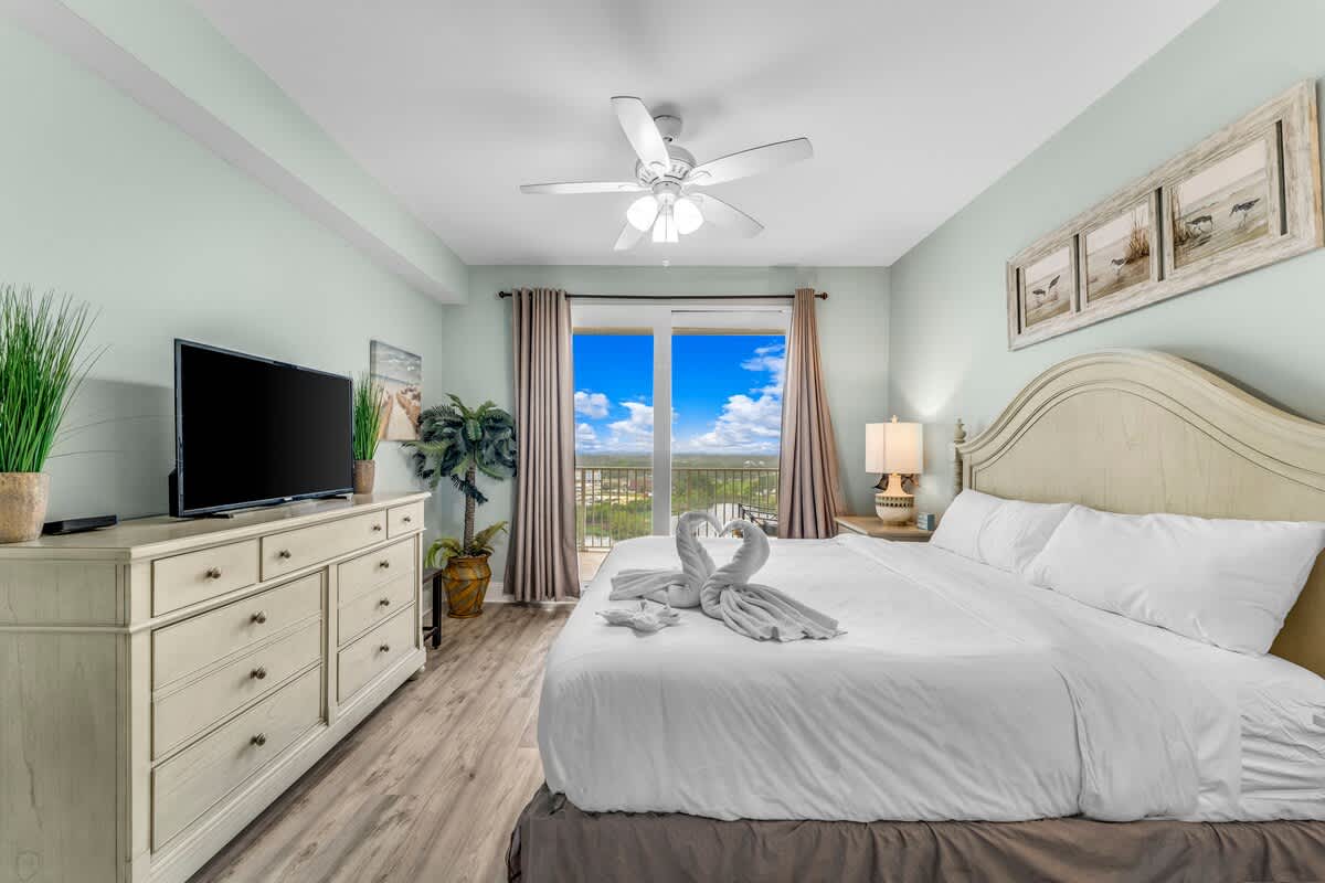 Laketown Wharf 1331 – Bright bedroom with a king bed, TV, dresser, and large windows offering a scenic view.