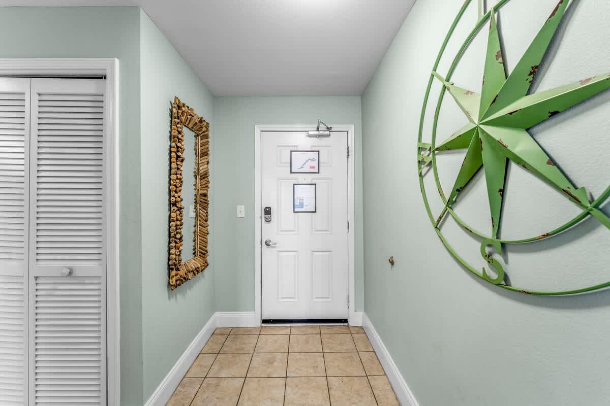 Laketown Wharf 1331 – Entrance hallway with tile floor, green walls, decorative mirror, and large compass wall art.
