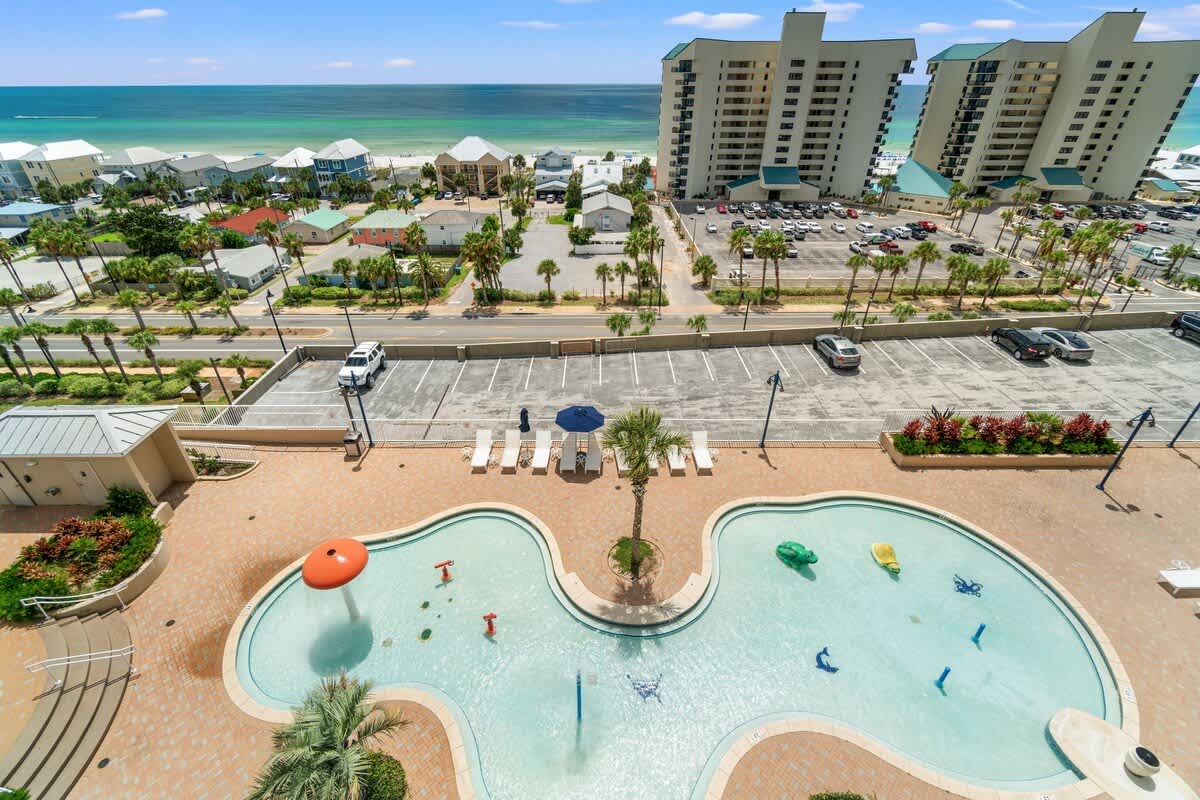 Laketown Wharf 1331 – View from balcony featuring a pool, lawn chairs, and ocean in the background.