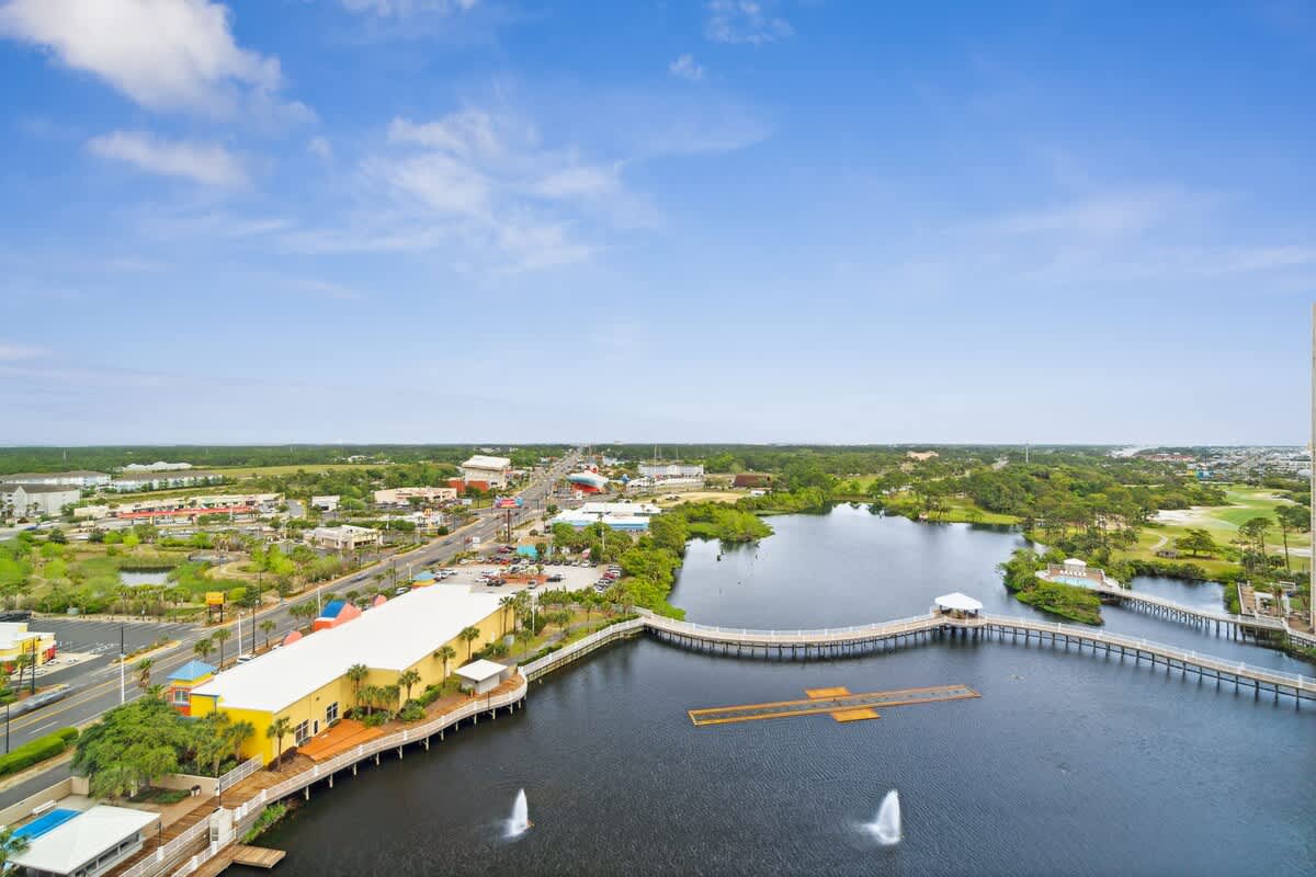 Laketown Wharf 1331 – Aerial view of waterfront, featuring residential buildings, road, and lush greenery under a clear blue sky.