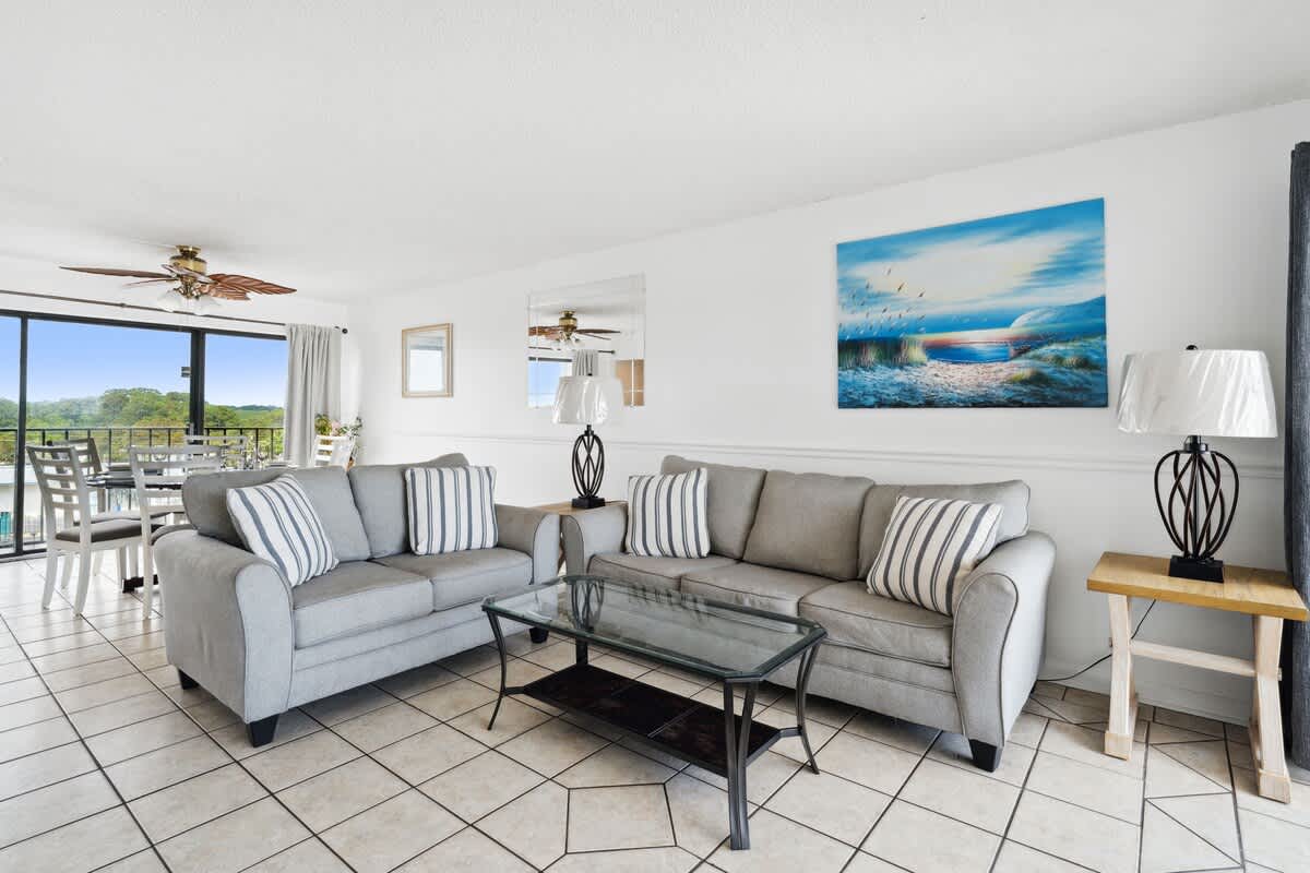 Moondrifter 608 – Living room with two gray sofas, glass coffee table, artwork, and view of the balcony.