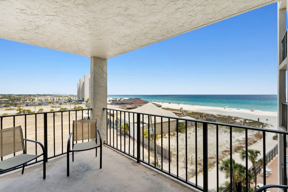 Moondrifter 608 – Balcony view showing beach, ocean, and nearby buildings with two chairs.