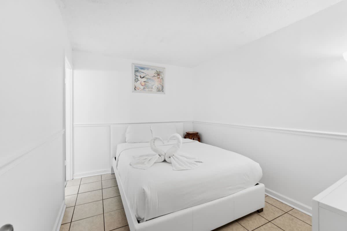 Moondrifter 608 – Cozy bedroom with a queen bed, decorative towel swans, and textured white walls.