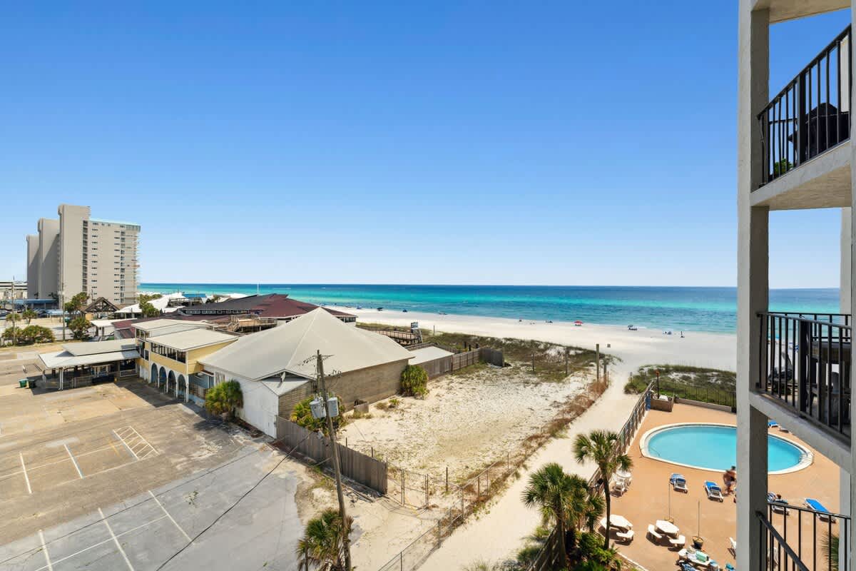 Moondrifter 608 – View of beach, ocean, pool, and surrounding buildings from a balcony.