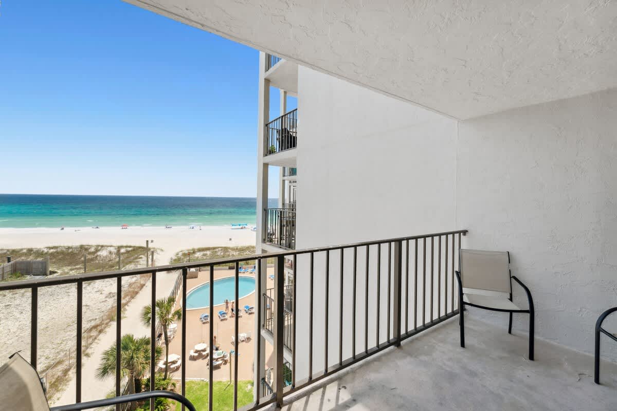 Moondrifter 608 – Balcony view overlooking beach, pool area, and ocean in a vacation rental.