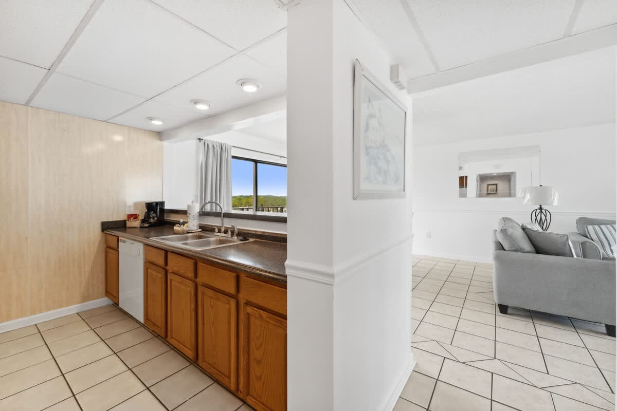 Moondrifter 608 – Open kitchen with wooden cabinets, adjacent living area, and large window showcasing a green view.