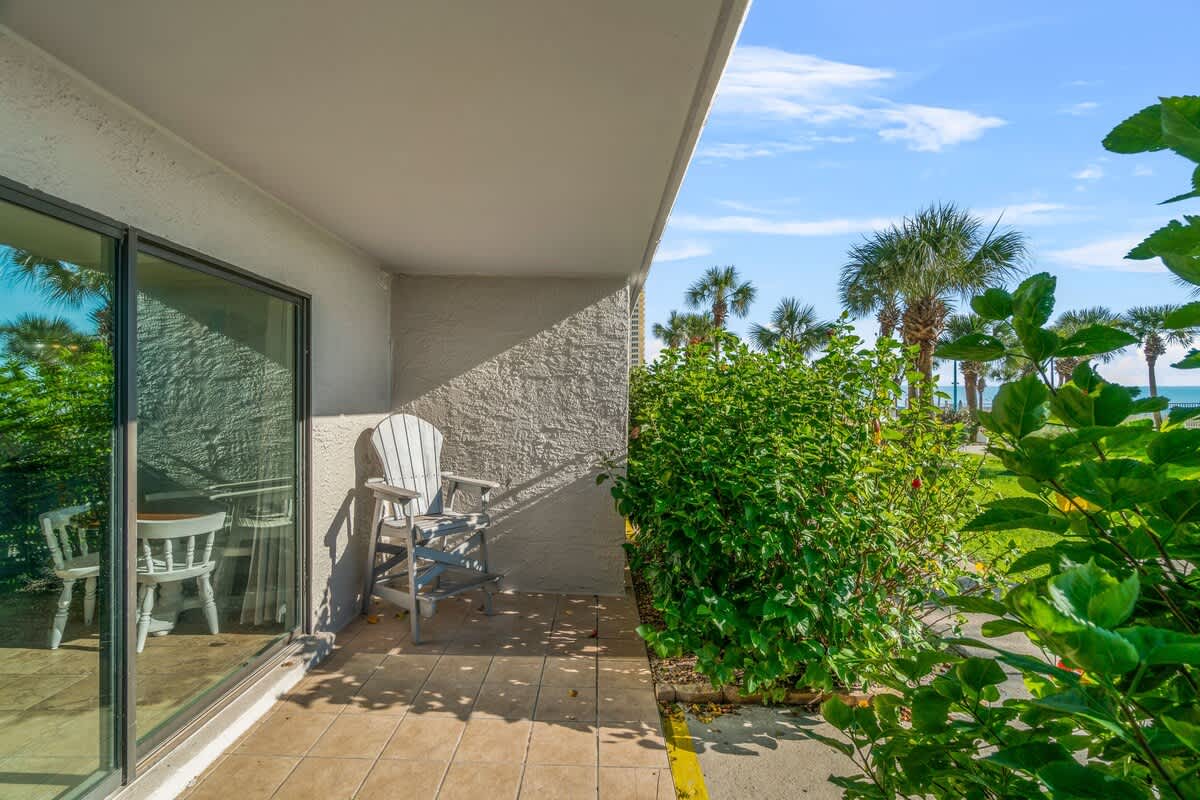 The Summit 105 – Patio with a white chair, potted plants, views of palm trees, and partial ocean view.
