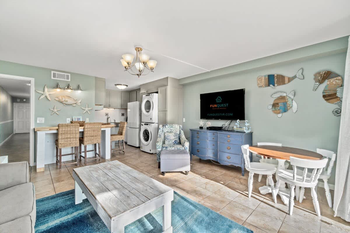 The Summit 105 – Cozy living area with sofa, dining table, kitchen bar, and washer/dryer; decorative fish on wall.