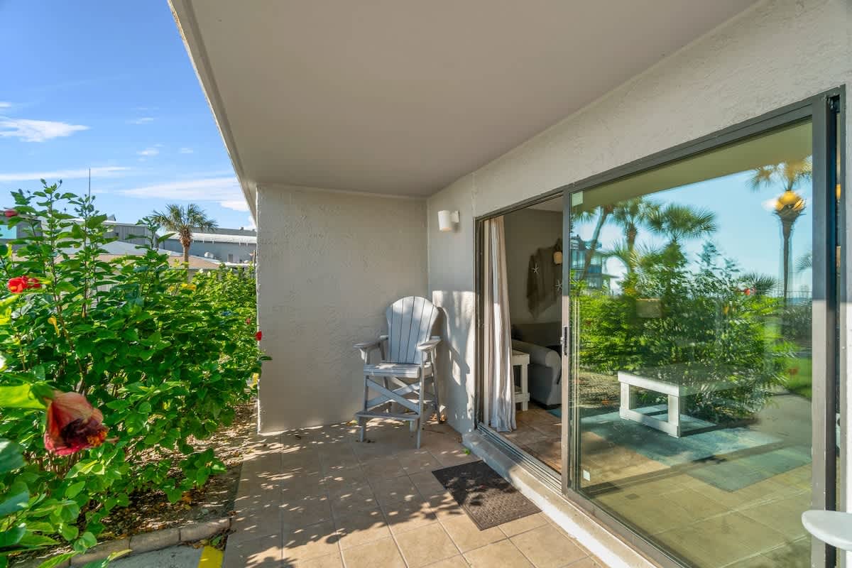 The Summit 105 – Ground-floor patio with outdoor chair, sliding glass door, view of greenery and palm trees.