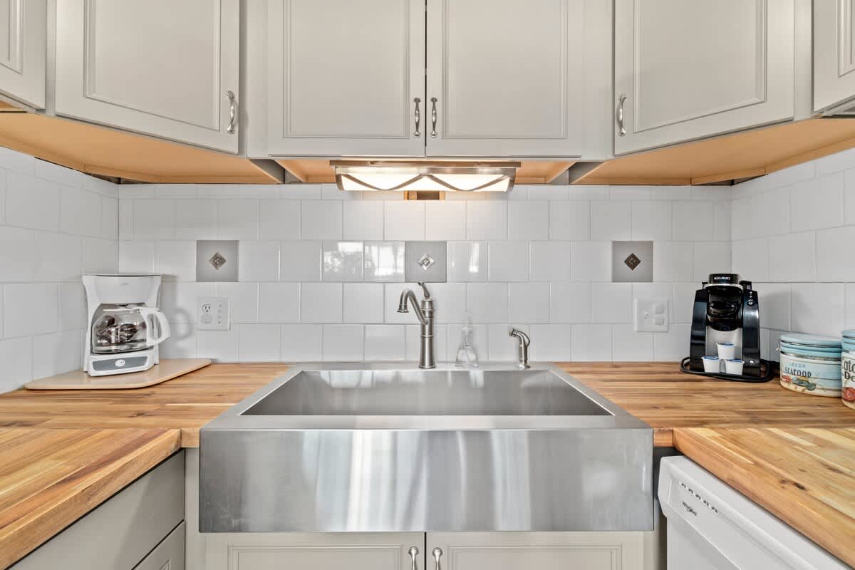 The Summit 105 – Modern kitchen featuring stainless steel sink, wooden countertops, coffee maker, and white tile backsplash.