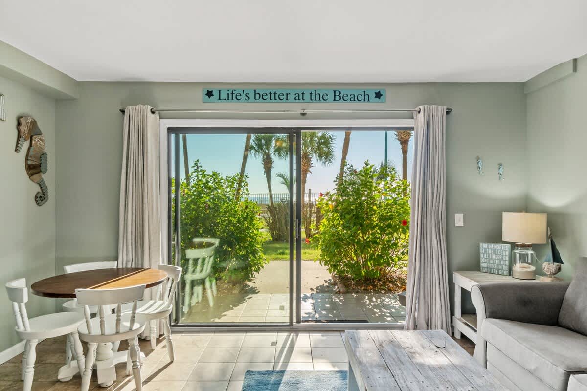The Summit 105 – Cozy living area with a dining table, palm view through glass doors, and beach decor accents.