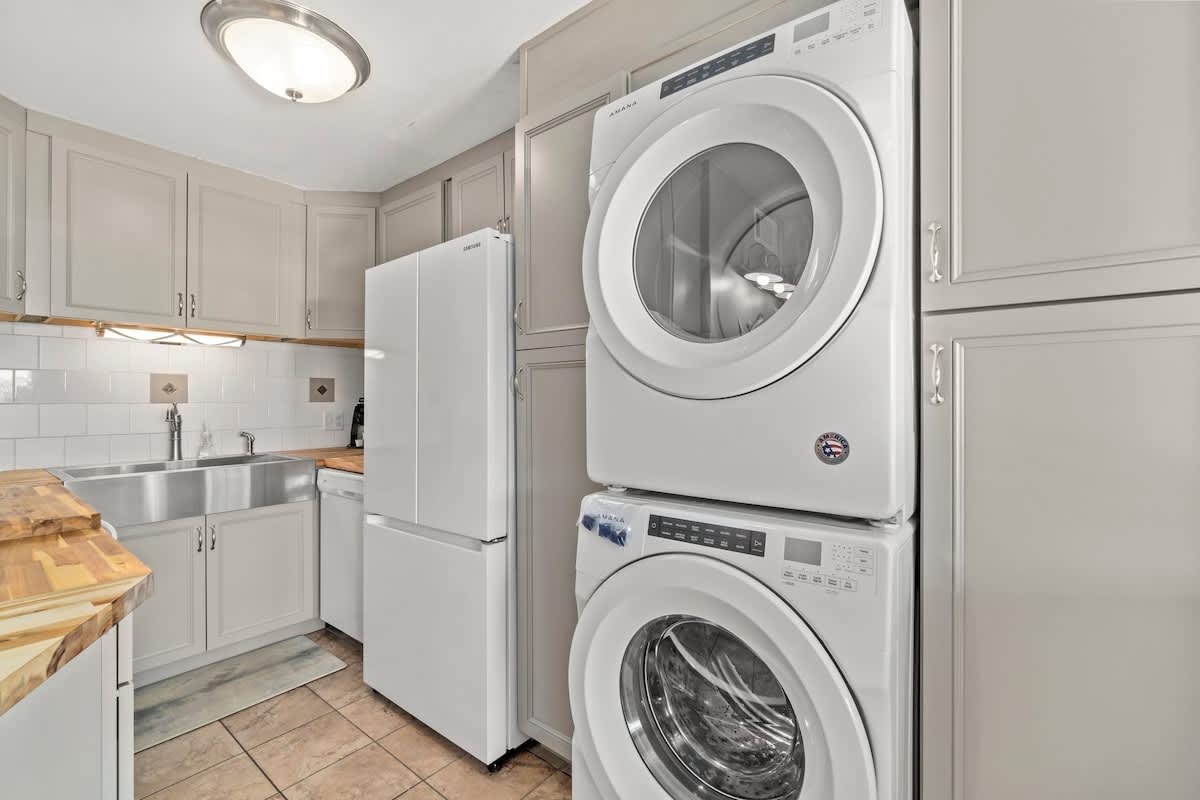 The Summit 105 – Modern kitchen with stainless steel appliances and stacked washer/dryer unit.