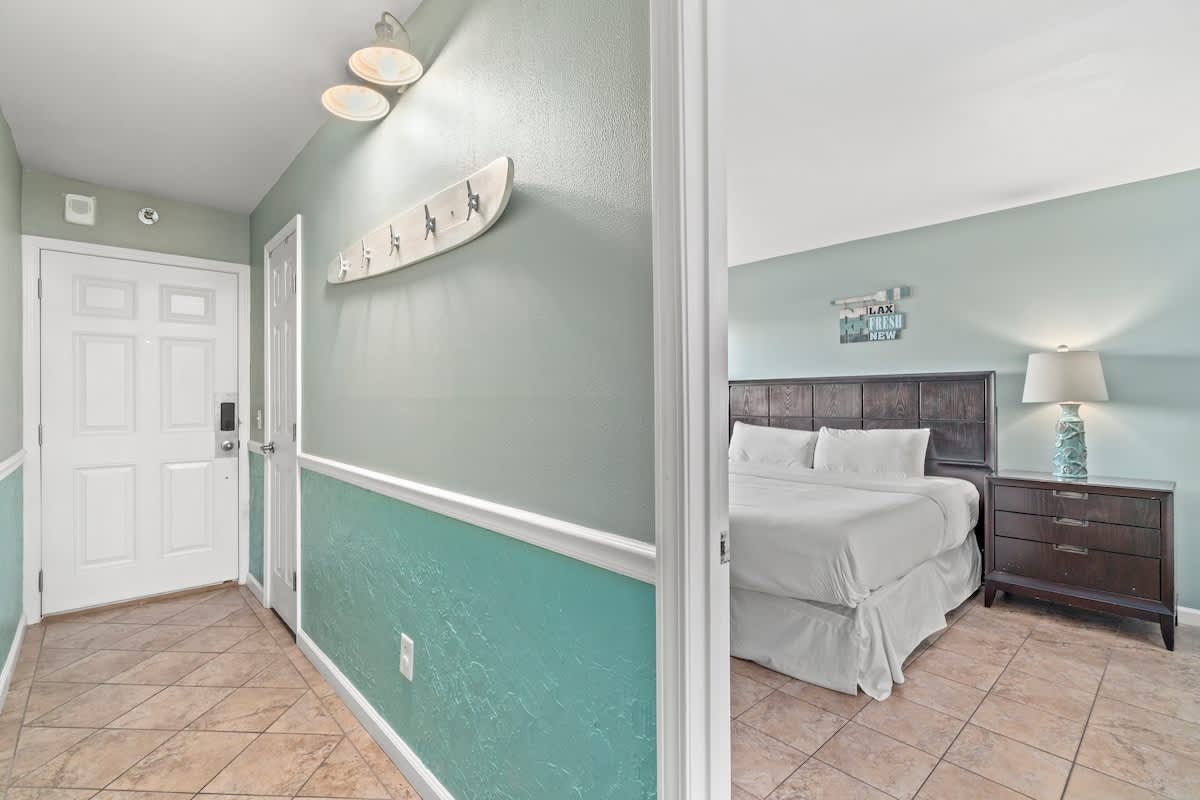 The Summit 105 – Entryway leading to a bedroom with a bed, nightstand, and decorative wall art.