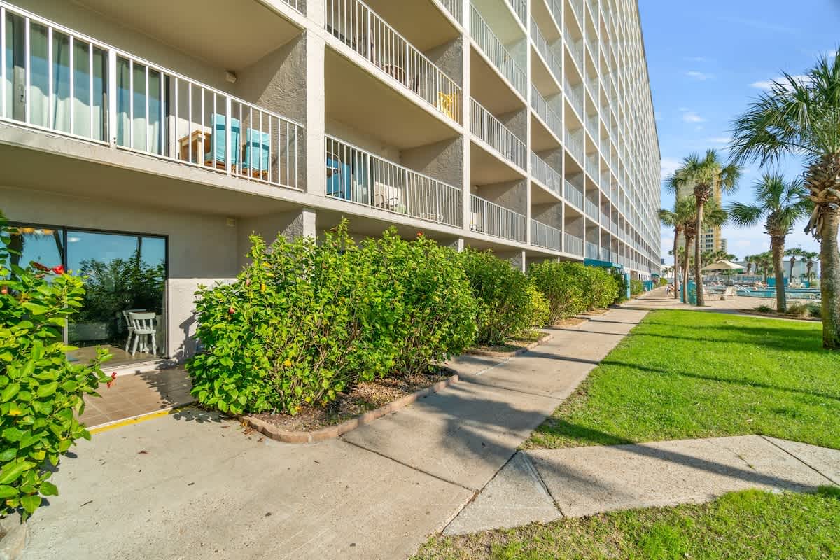 The Summit 105 – Exterior view of a vacation rental with balconies and greenery, leading to a pool area.