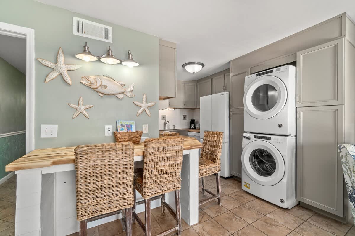 The Summit 105 – Kitchen area with washer and dryer, wooden dining table, and decorative fish and starfish wall art.