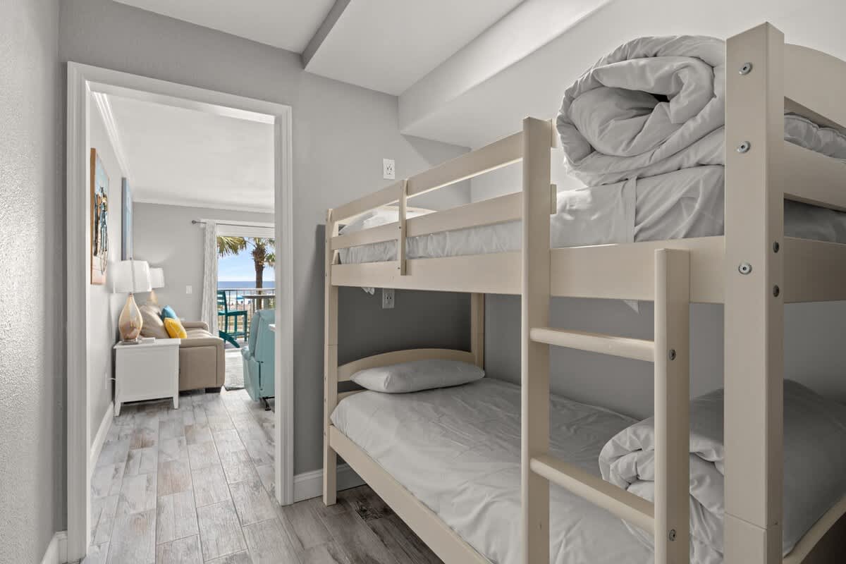The Summit 228 – Bunk bed room with view of patio and palm trees through an open doorway.