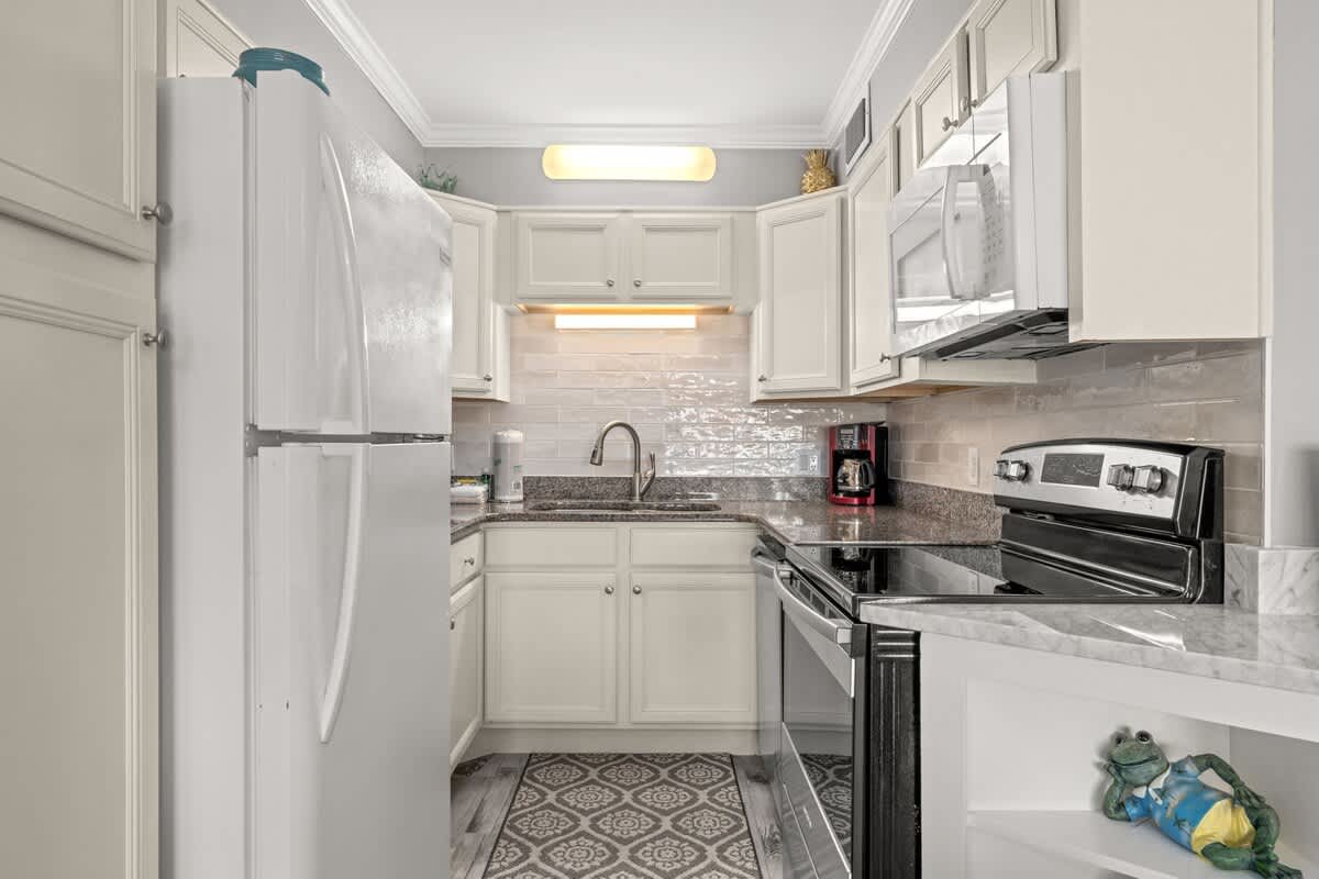 The Summit 228 – Compact kitchen with white appliances, granite countertops, and decorative tile flooring.