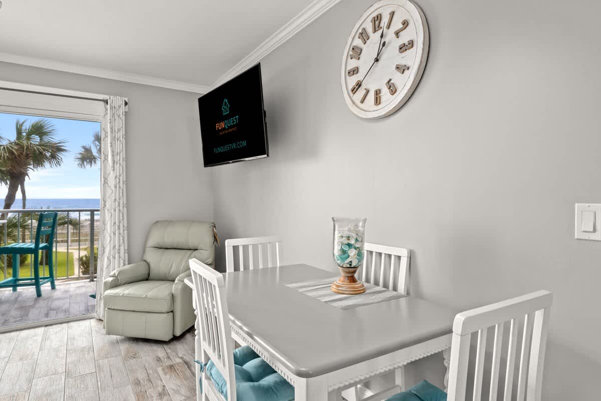 The Summit 228 – Cozy dining area with a table, chairs, and ocean view through sliding glass doors.
