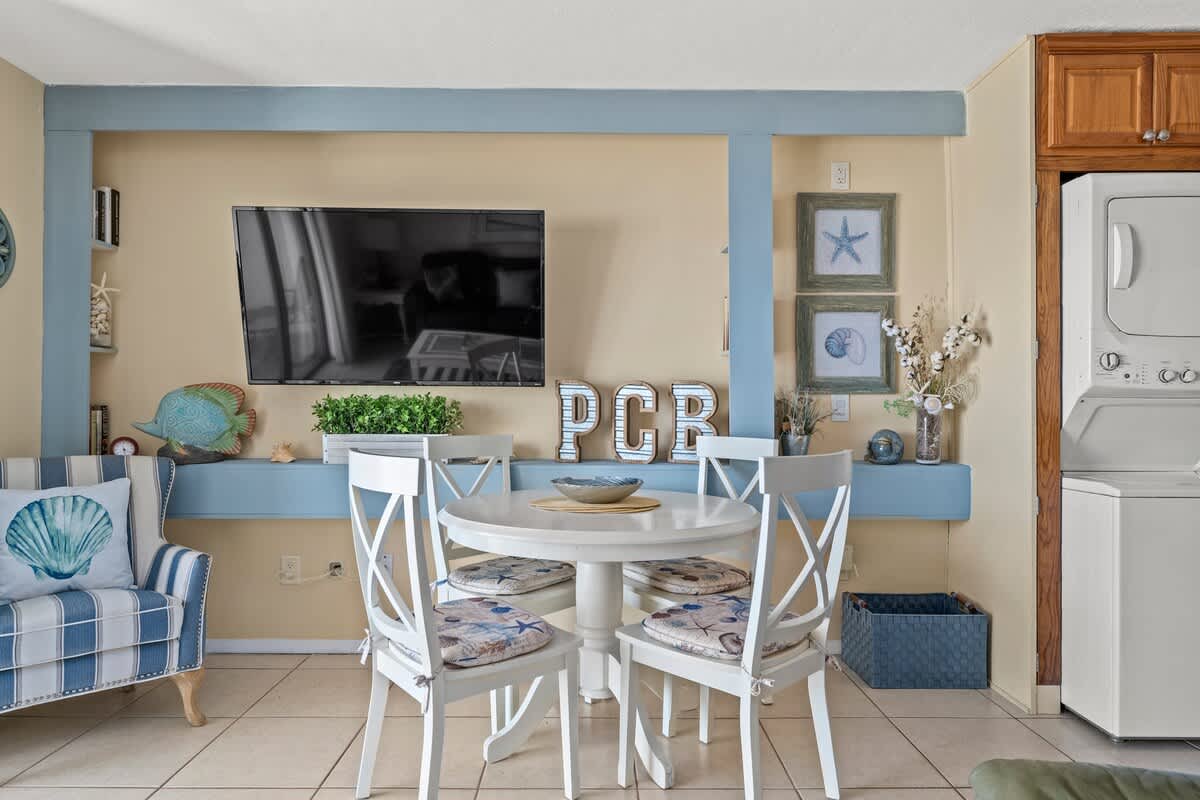 The Summit 506 – Cozy dining area with a round table, four chairs, a TV, and a washer/dryer unit in view.