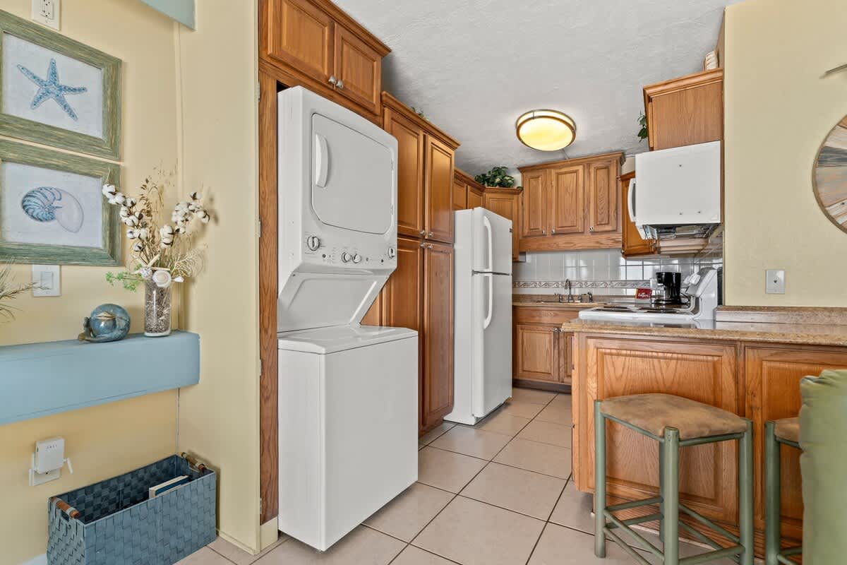 The Summit 506 – Compact kitchen area with wooden cabinets, laundry machines, and a small dining nook.