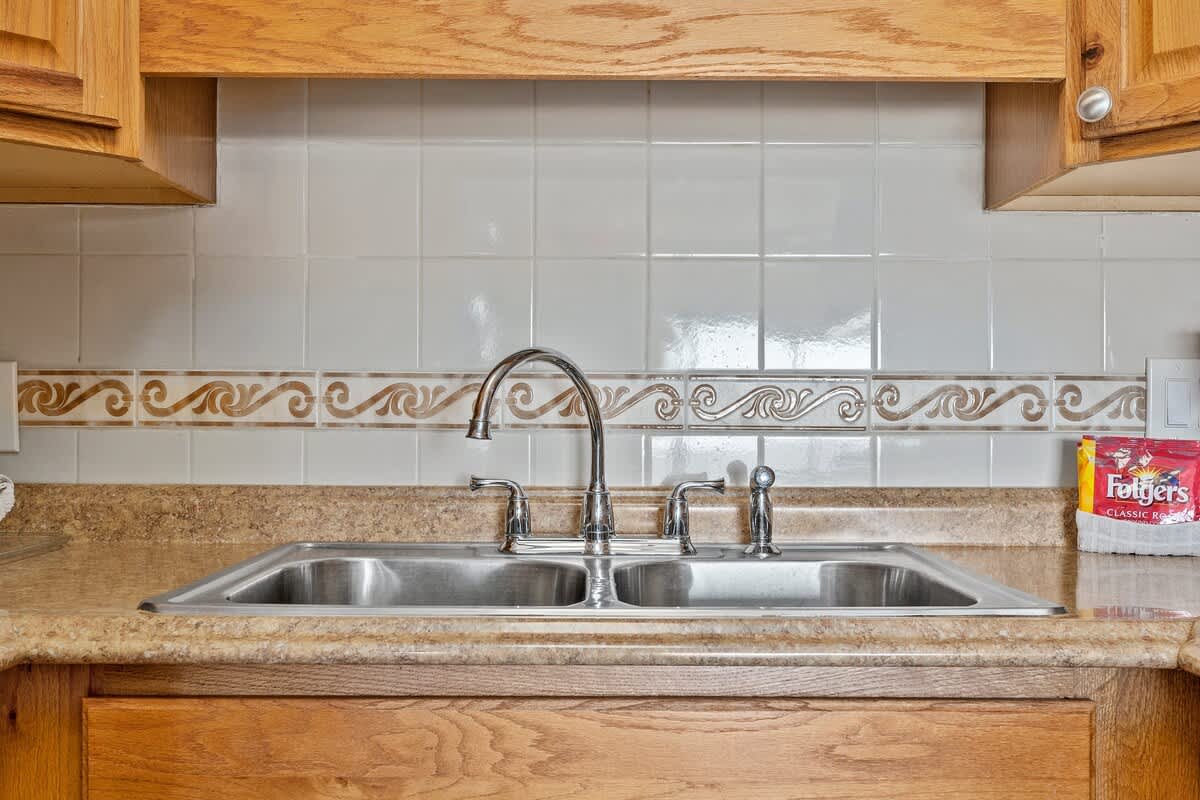 The Summit 506 – Kitchen sink with faucet, surrounded by wooden cabinetry and backsplash tiles, featuring a coffee package.
