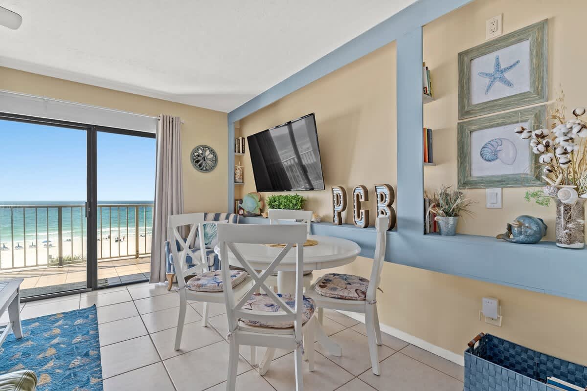 The Summit 506 – Cozy dining area with beach views, a table, chairs, and a wall-mounted TV.