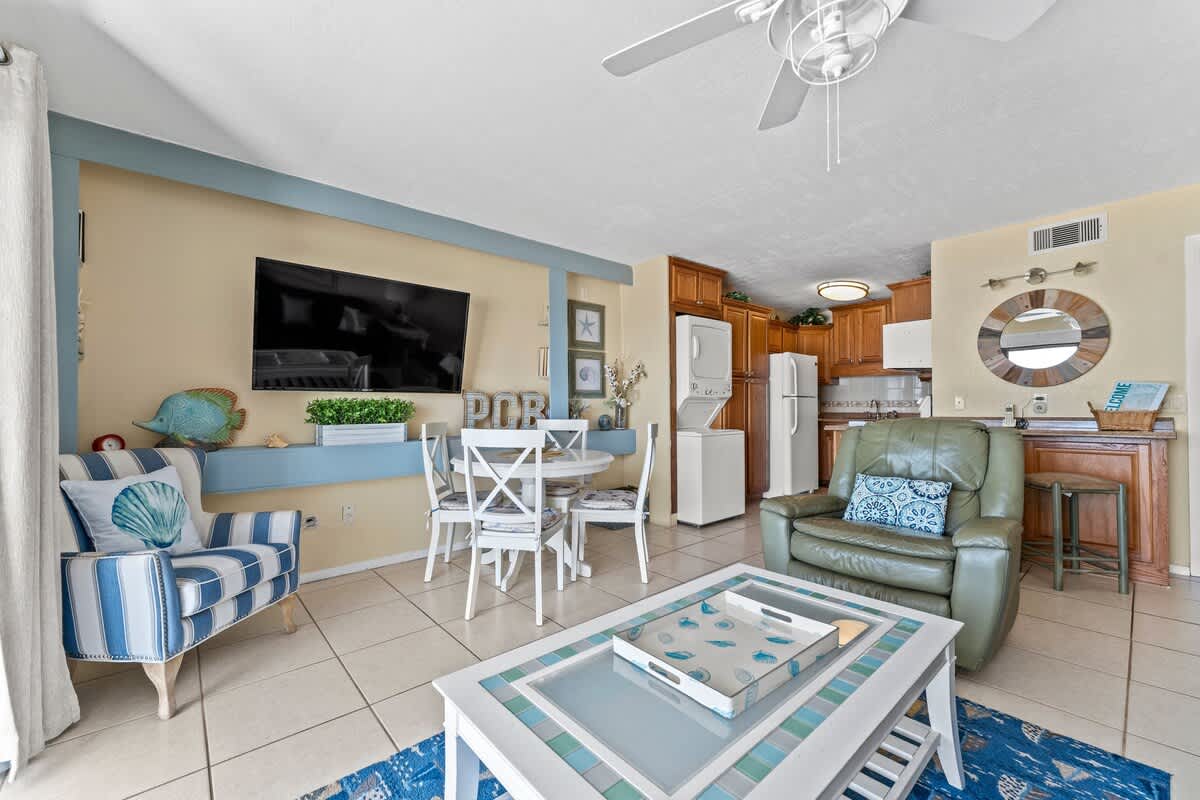 The Summit 506 – Cozy living area with green recliner, dining table, kitchenette, and blue-striped decor.