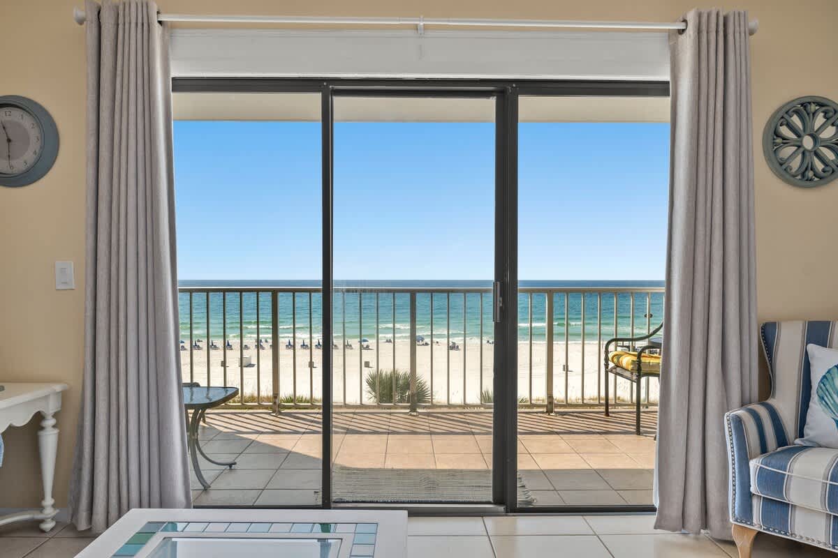 The Summit 506 – Beach view from a balcony with a sliding glass door, overlooking sand and ocean.