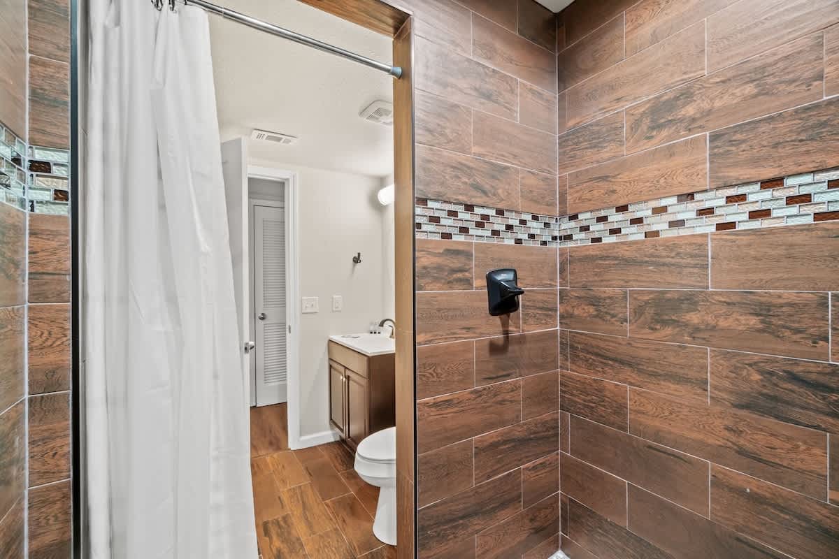 5218 Beach Dr A – Modern bathroom featuring a walk-in shower, vanity with sink, and wooden tile flooring.