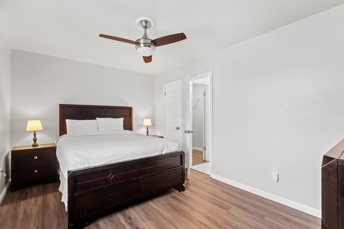 5218 Beach Dr A – Bedroom featuring a queen bed, bedside lamps, wooden dresser, and an adjoining bathroom door.