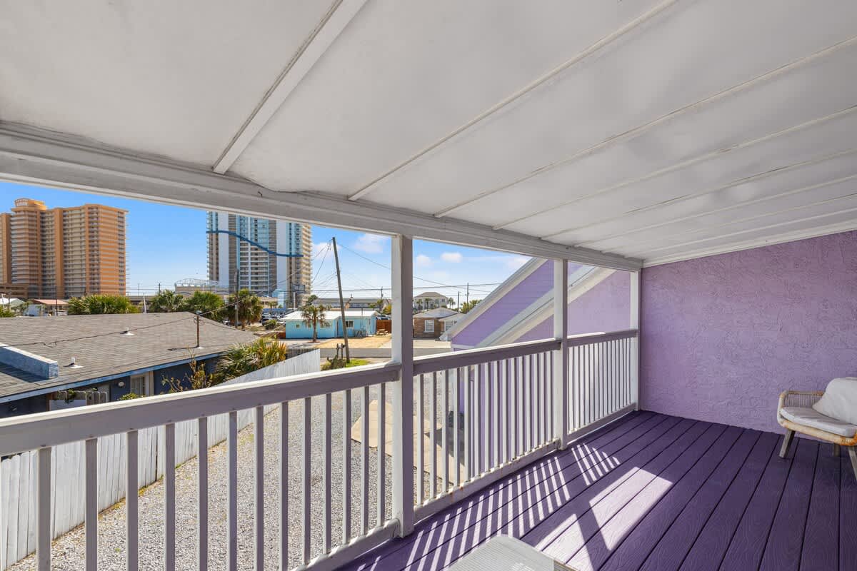 5218 Beach Dr C – View from a balcony showing purple floor, white railing, and surrounding buildings.
