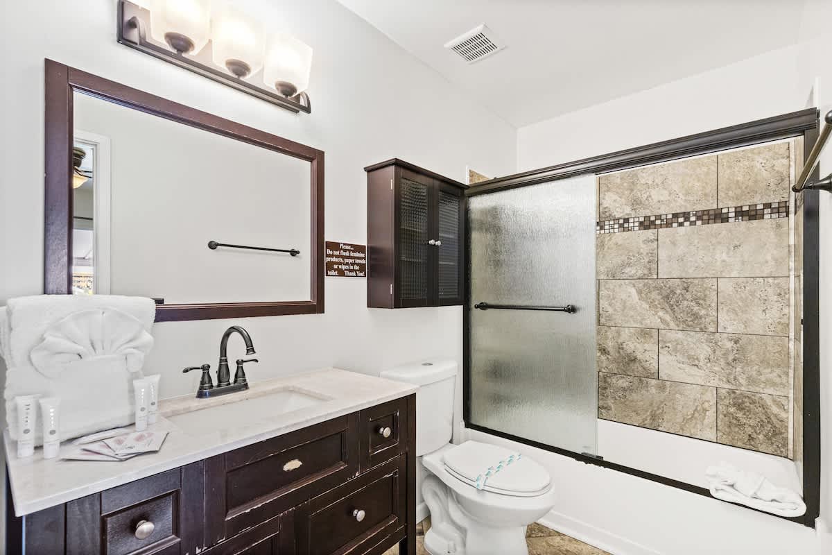 5218 Beach Dr C – Bathroom with a sink, toilet, shower, and decorative tiles.
