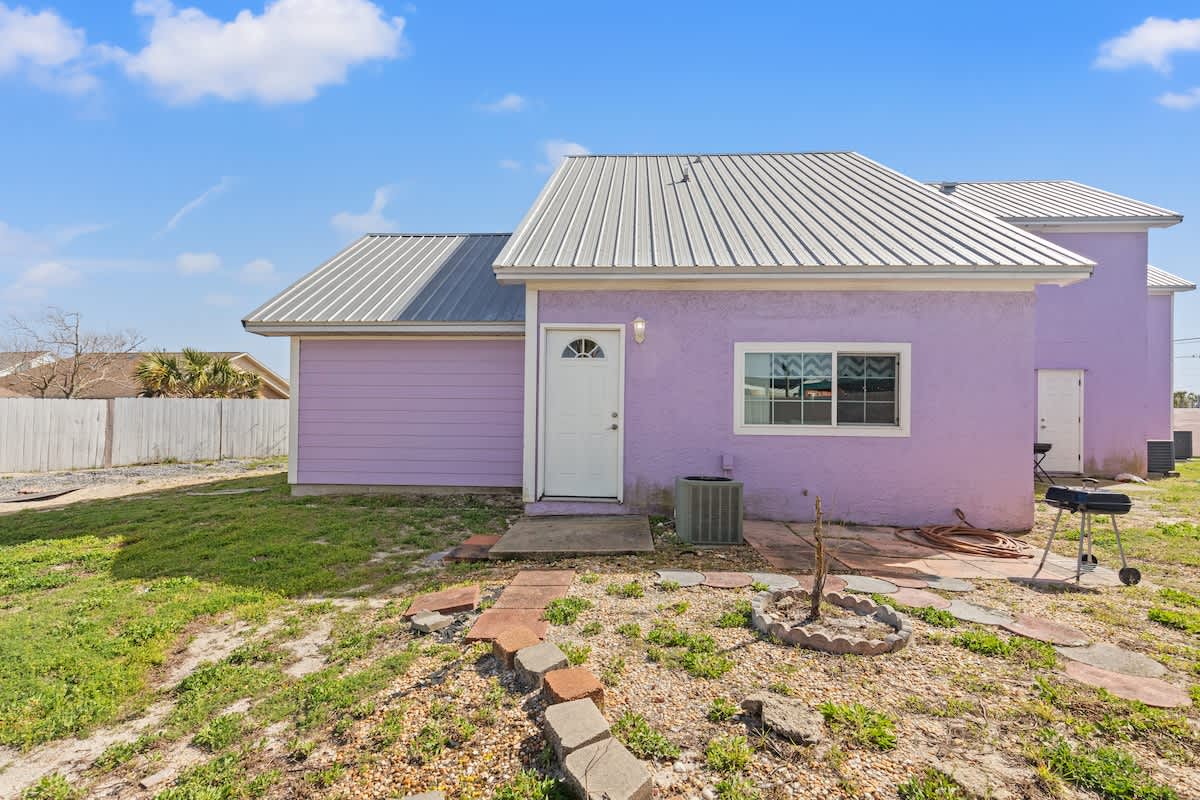 5218 Beach Dr C – Purple house exterior with a metal roof, front door, and small yard featuring landscaping stones.