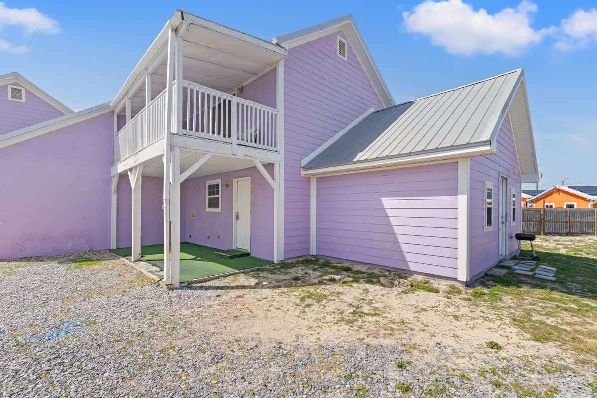 5218 Beach Dr C – Exterior view of a purple vacation rental with a covered balcony and grassy outdoor area.