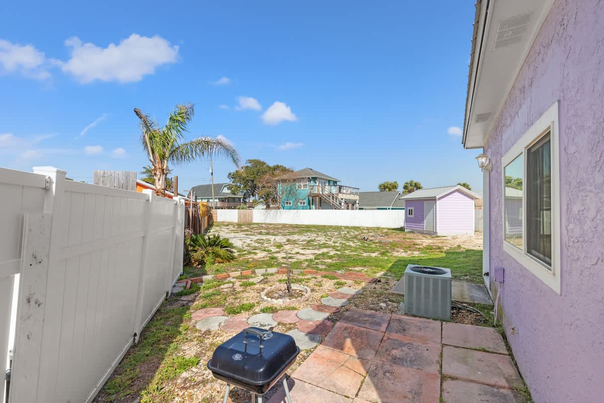 5218 Beach Dr C – Backyard area with a grill, stepping stones, and a view of surrounding houses and clear blue sky.