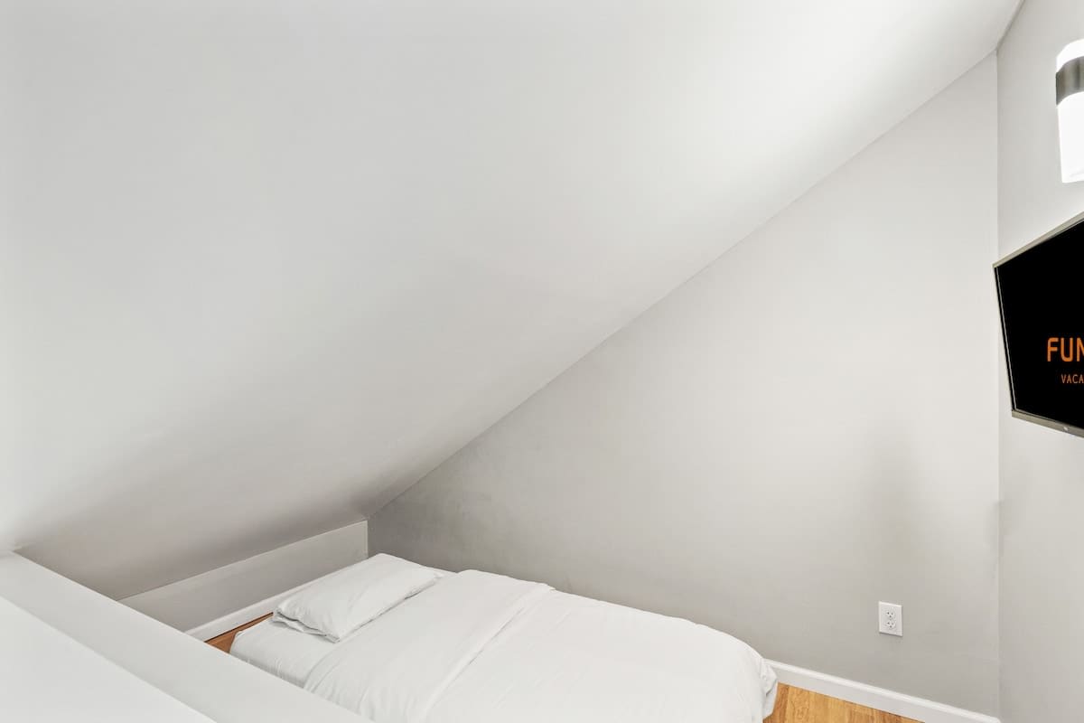 5218 Beach Dr C – Cozy attic bedroom with slanted ceiling, double bed, and wall-mounted TV.