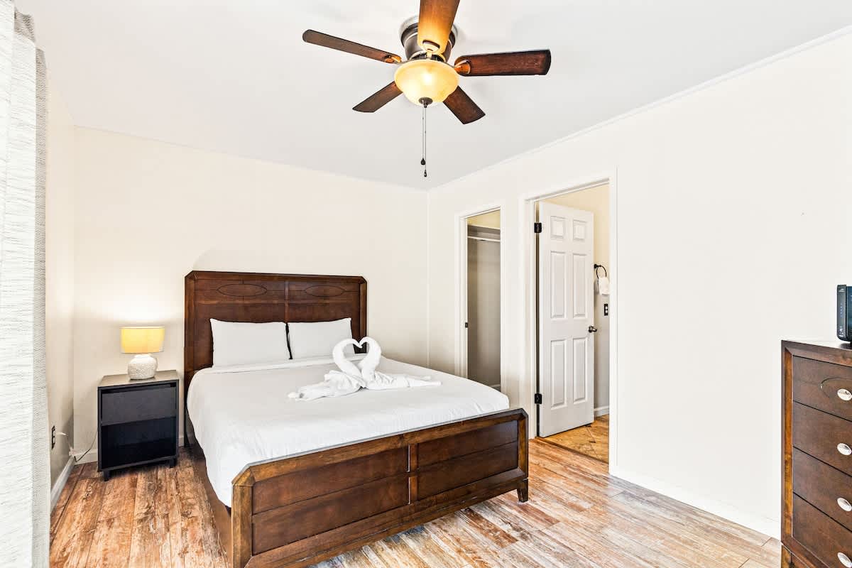 5218 Beach Dr C – Bedroom featuring a wooden bed, nightstand, ceiling fan, and dresser, with an open closet door.