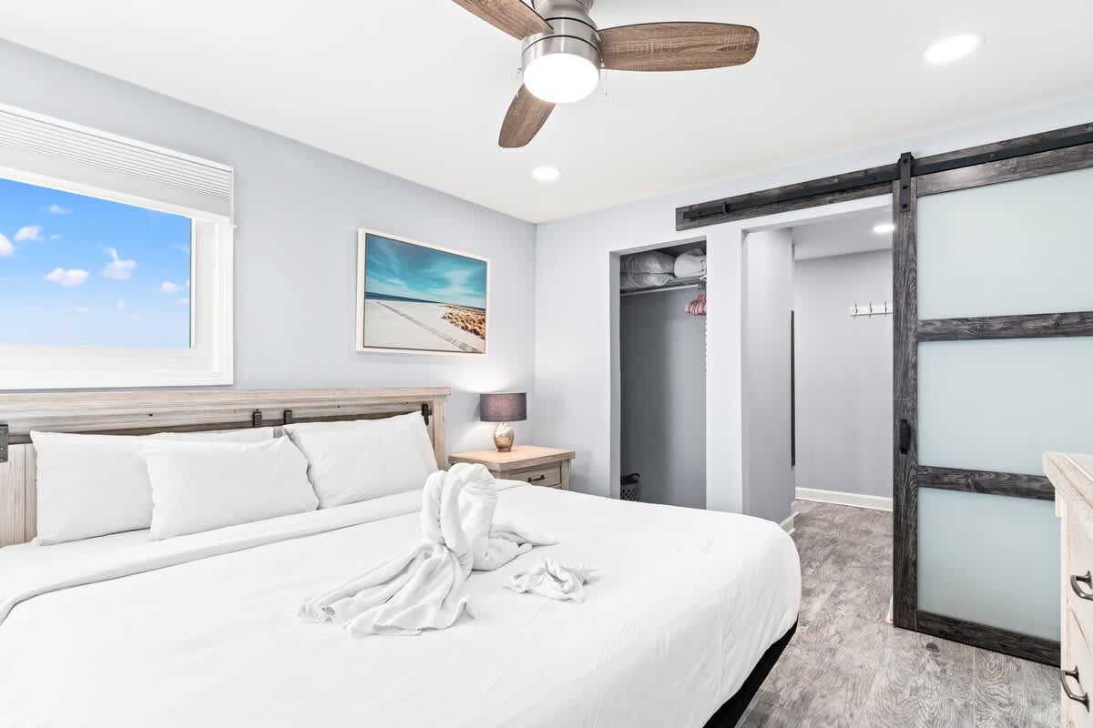 The Summit 701 – Bedroom with a bed, ceiling fan, nightstand, closet, and window featuring blue sky view.