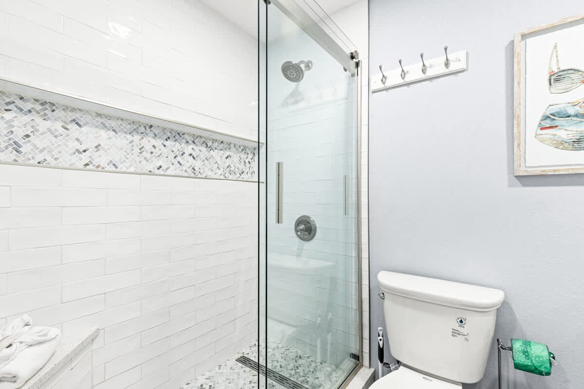 The Summit 701 – Modern bathroom featuring a glass shower, white tile walls, and a toilet.