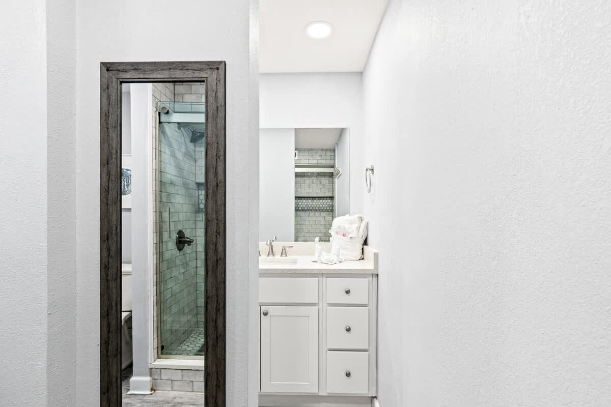 The Summit 701 – Bathroom with glass shower, white vanity, and light gray walls.