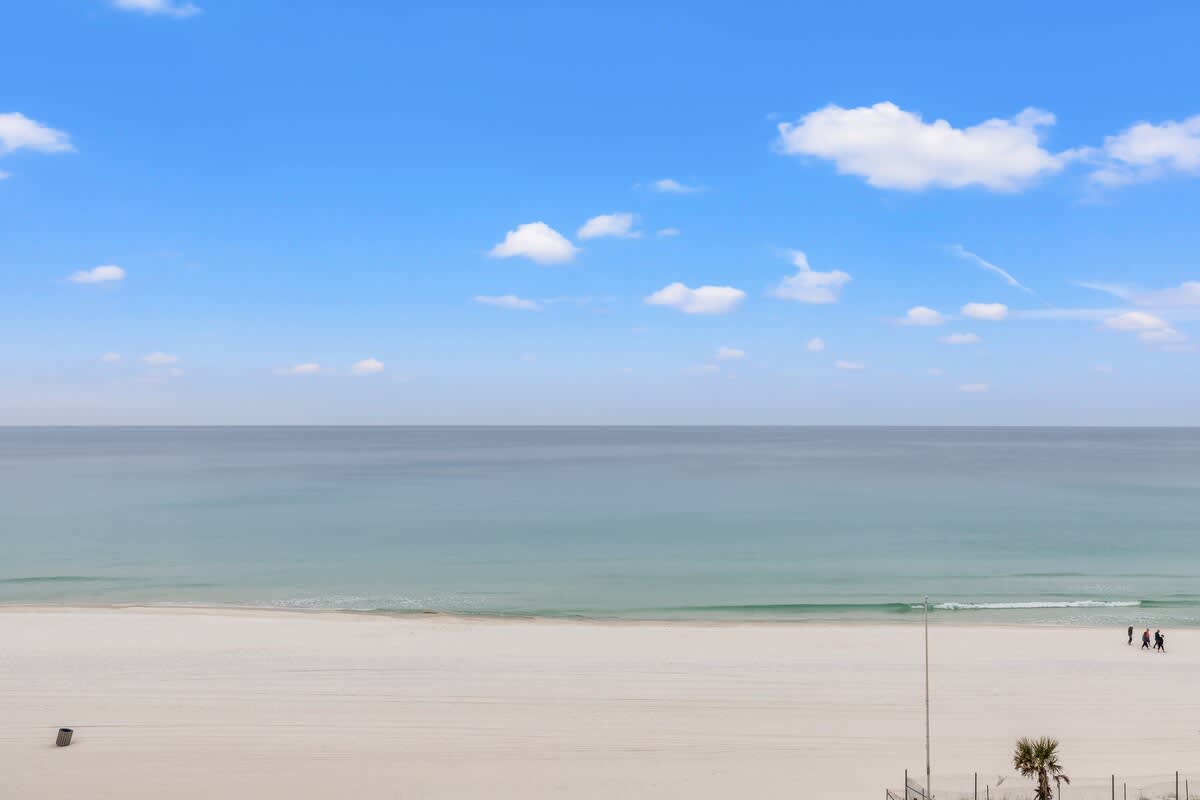The Summit 701 – Ocean view from balcony with sand beach and distant figures walking by the water.